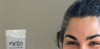 Tattooed woman with dark hair holding a wrapped chocolate bar