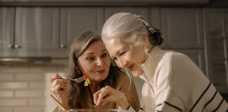 Women eating fruit salad in the kitchen.