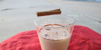 A glass of eggnog sitting on a table.