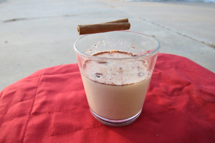 A glass of eggnog sitting on a table.