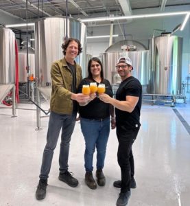 A photo of three people holding beers.