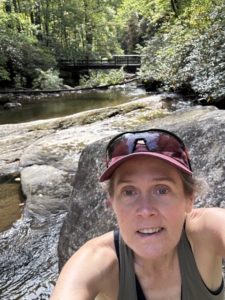 A person taking a picture by a creek.