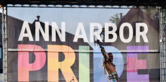 A person next to a Ann Arbor Pride banner.