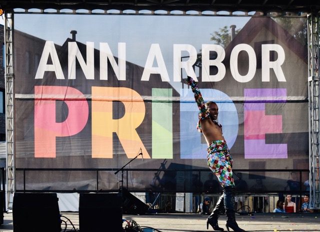 A person next to a Ann Arbor Pride banner.