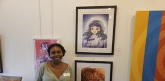 An Artist standing next to their paintings