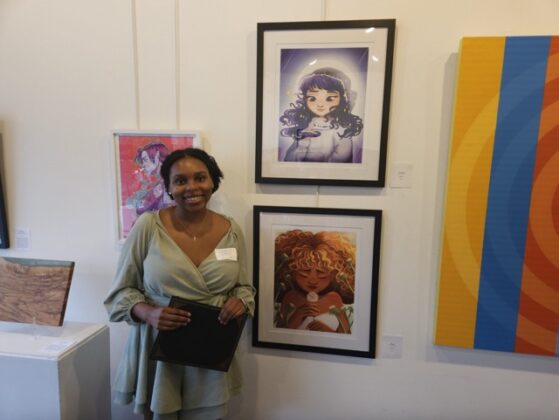 An Artist standing next to their paintings