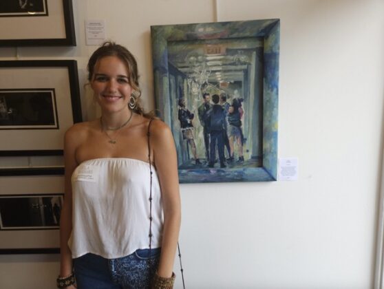 An artist standing near their painting.