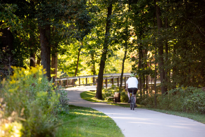 Bicyclist on paved trail in woods