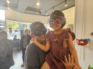 child in mask being lifted by her father