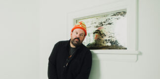 Man in orange hat in front of photo and white wall