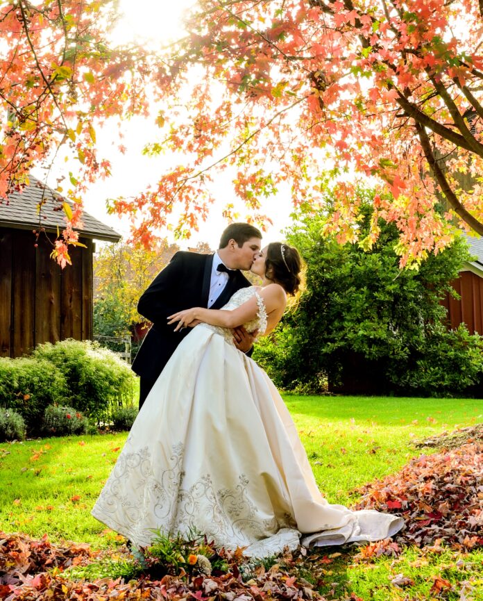 bride and groom under fall tree