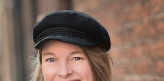 Woman in hat with arms crossed and smiling