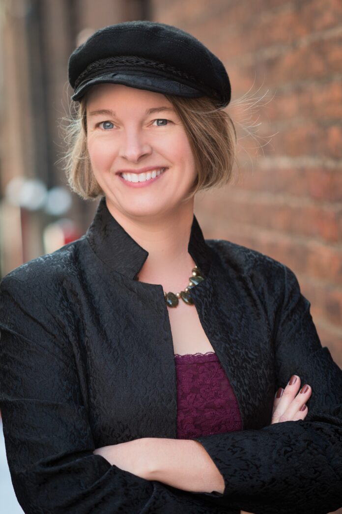 Woman in hat with arms crossed and smiling