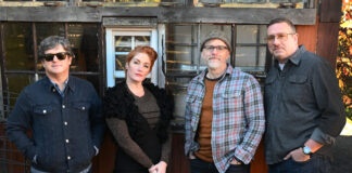 Four people standing in a row looking at camera
