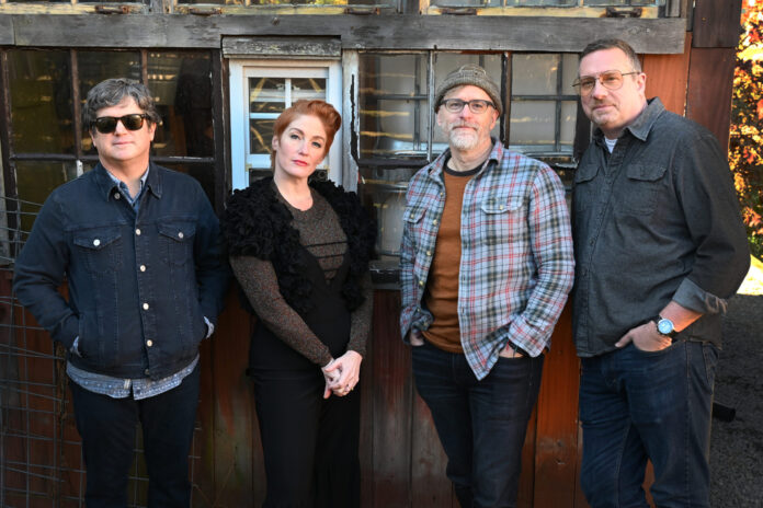 Four people standing in a row looking at camera