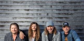 Four band members against rustic backdrop