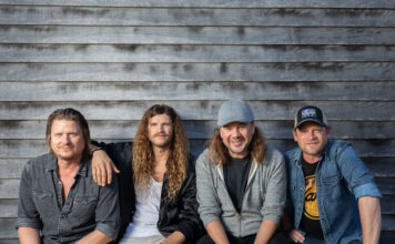 Four band members against rustic backdrop