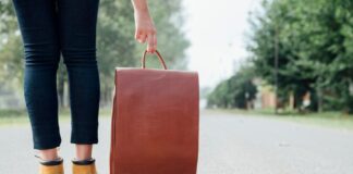 Human legs next to traveling bag on road