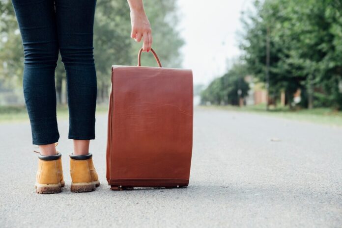 Human legs next to traveling bag on road