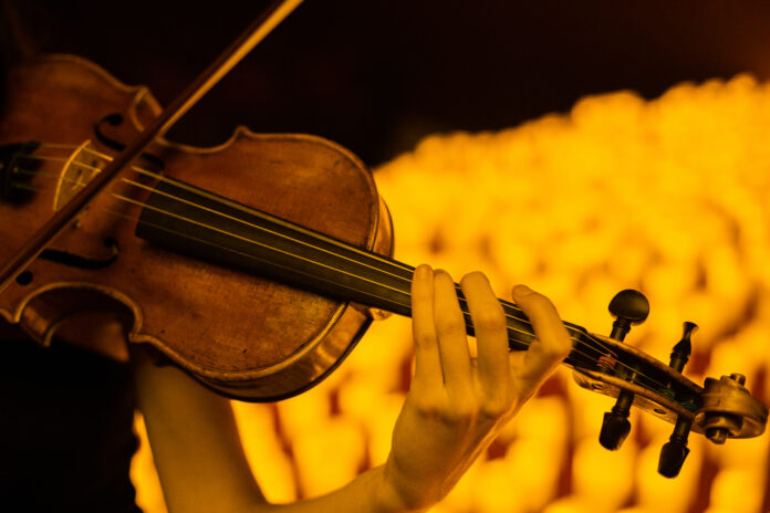 violin player arms surrounded by candles
