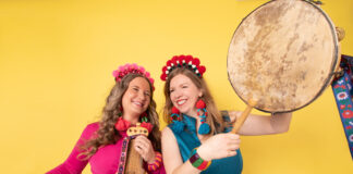 Two woman playing instruments against yellow backdrop