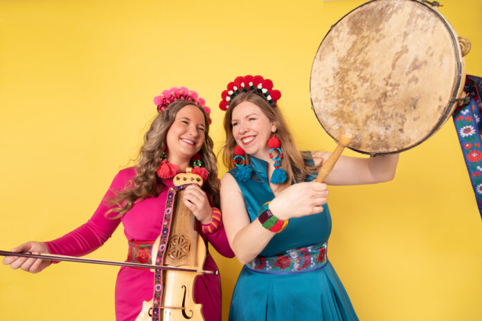 Two woman playing instruments against yellow backdrop