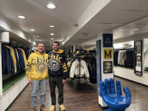 Two men standing in university of michigan gear in a vintage store