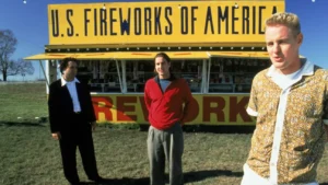 Three men in front of fireworks stand 