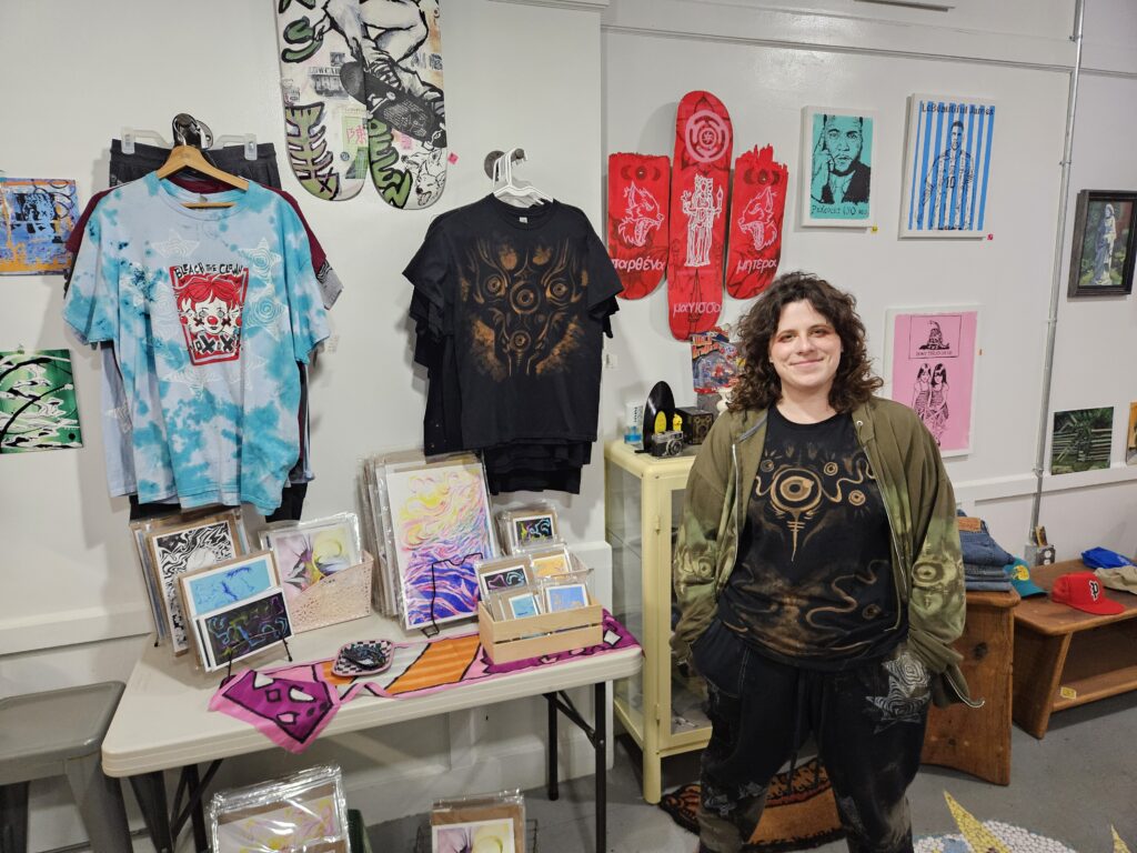 Andie Ziemkowski standing next to her unique t-shirts. 
