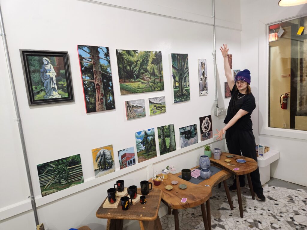 Sam Turner standing next to his paintings. 