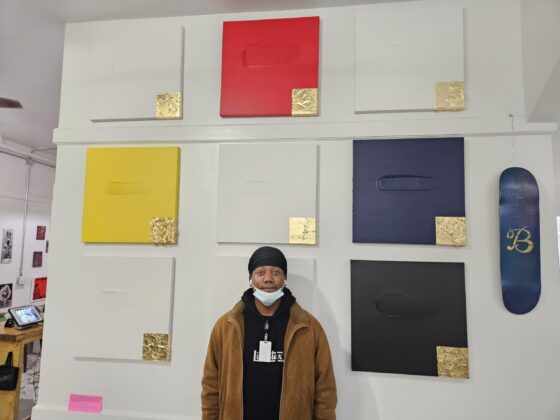 Frederick Lord standing in front of his canvases.