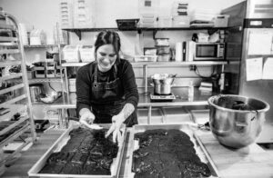 Black and white photo of woman baking in commercial kitchen 