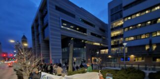 The rally outside of City Hall had a banner visible to passing motorists, who honked frequently in support. Photo by Drew Saunders