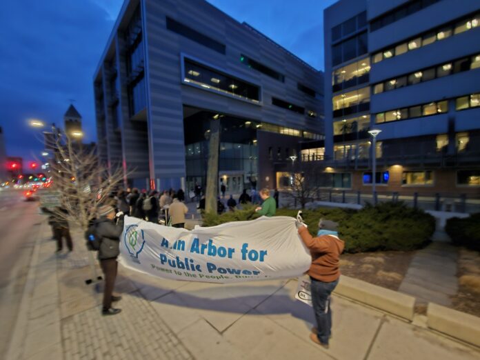The rally outside of City Hall had a banner visible to passing motorists, who honked frequently in support. Photo by Drew Saunders