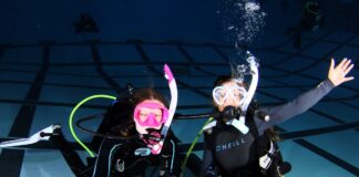 Two kids scuba diving in pool.