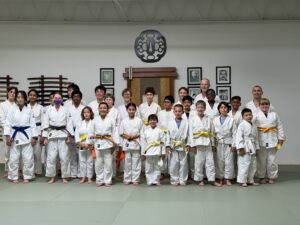 Group of students and instructors in their karate uniforms at a dojo.