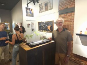 Brian Kirtzman standing alongside his Fisher With Eastern Hemlock, during the August 15 Chris Nordin Gallery opening reception. Photo by Drew Saunders
