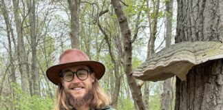 Man in woods holding large mushroom.
