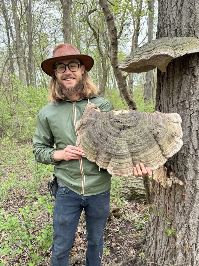 Man in woods holding large mushroom.